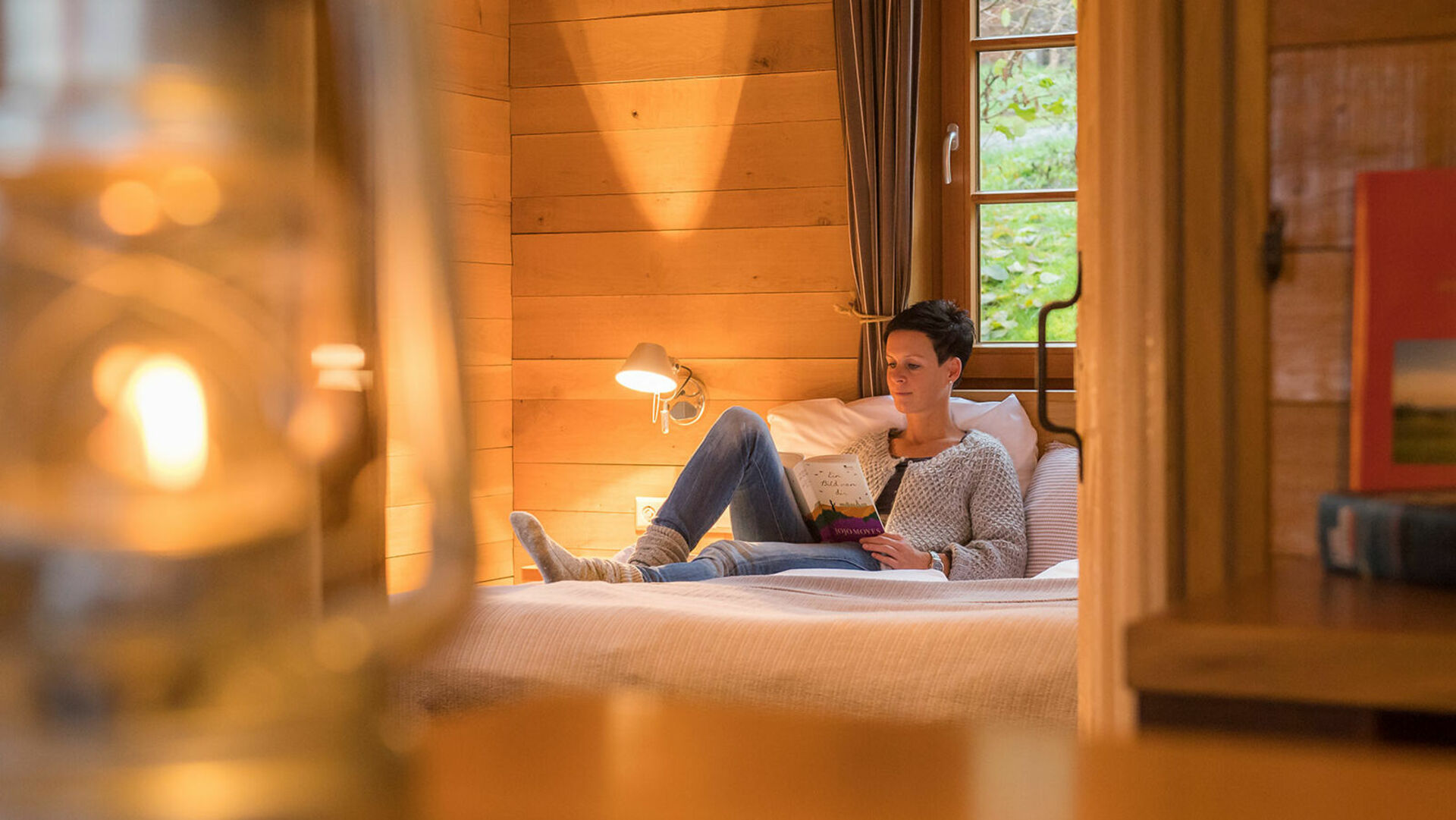 Hotelzimmer, Frau auf Bett mit Buch am lesen