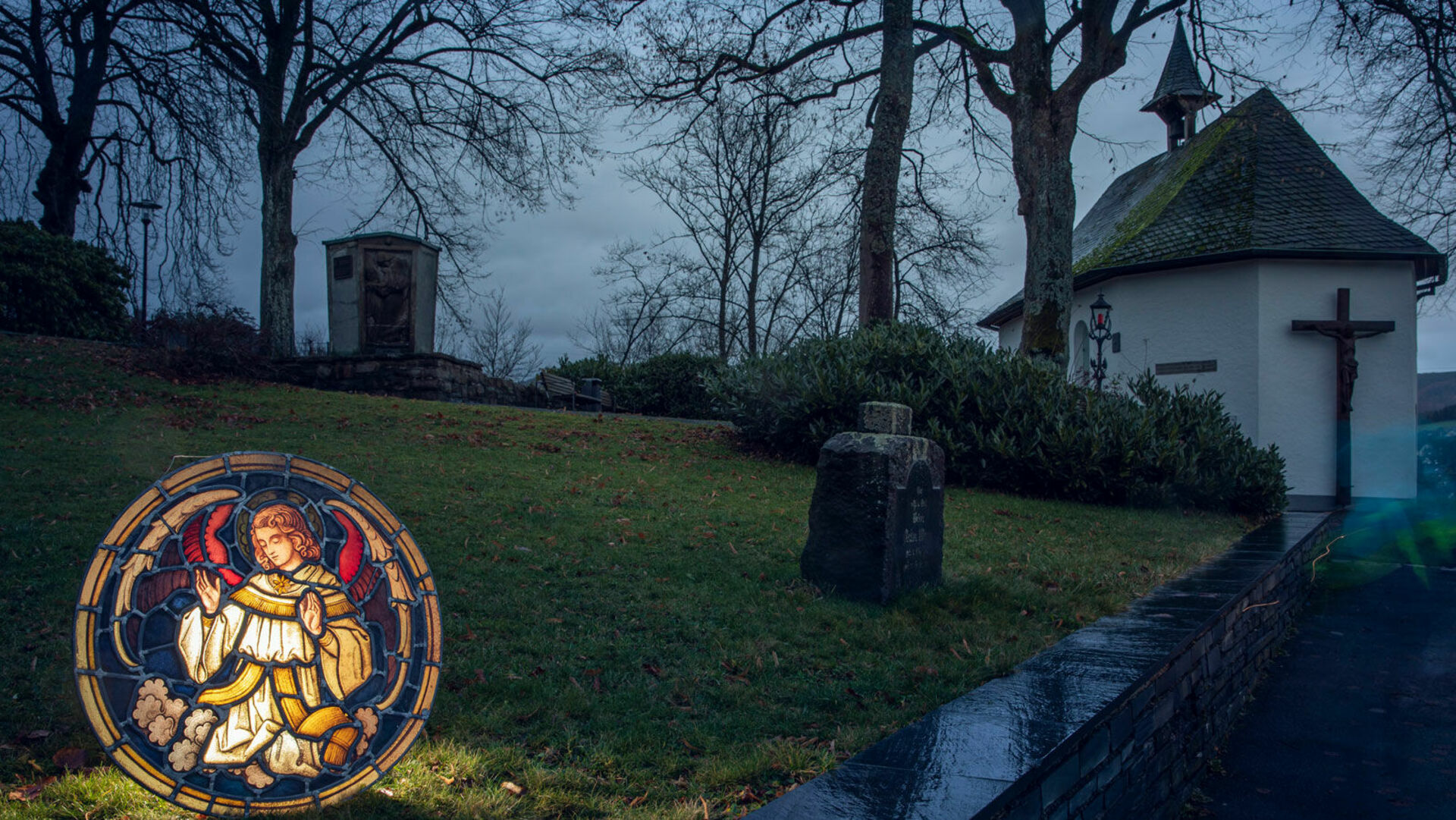 Beleuchtete Skulptur im Vordergrund, Kapelle im Hintergrund