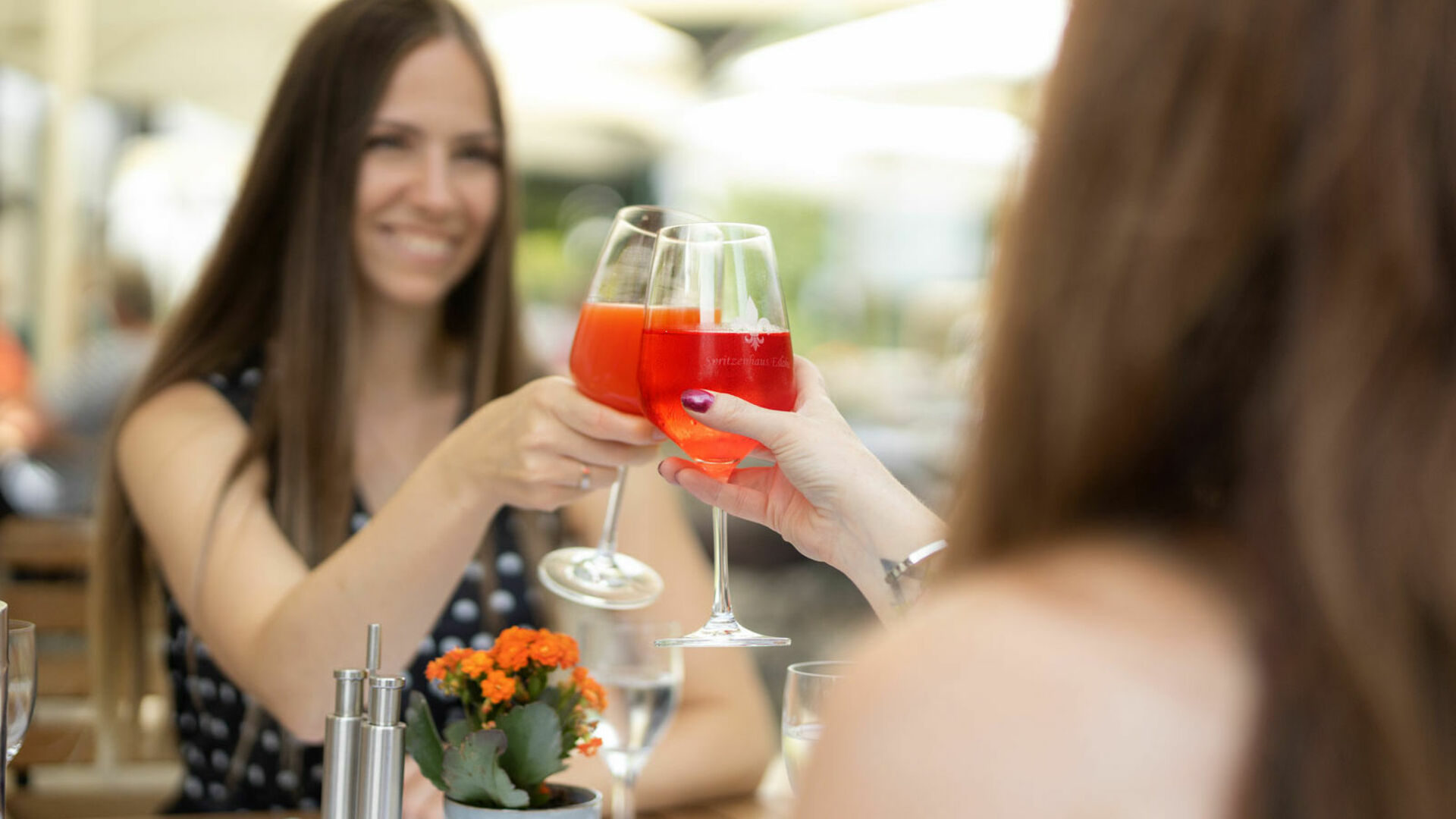 Zwei Frauen im Restaurant, stoßen an mit Gläsern 